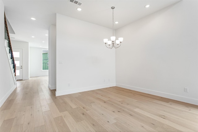 empty room featuring an inviting chandelier and light hardwood / wood-style flooring