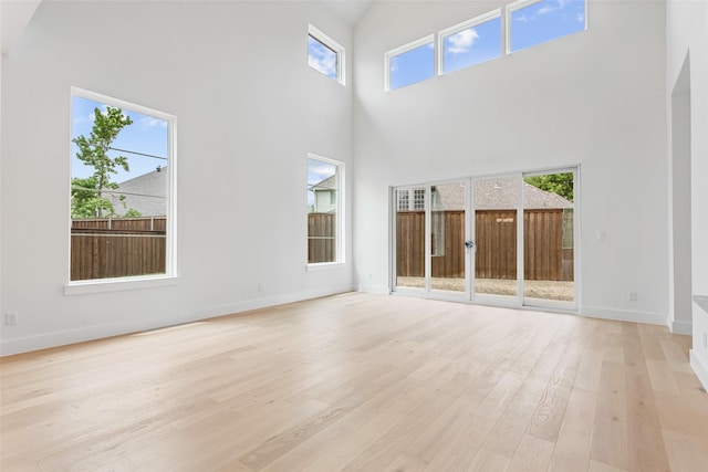 unfurnished living room featuring a towering ceiling and light hardwood / wood-style flooring