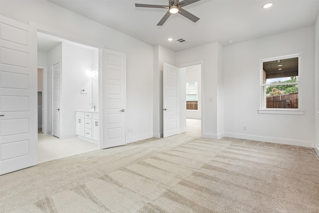 unfurnished bedroom featuring ceiling fan, light colored carpet, and ensuite bathroom