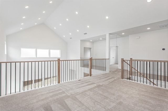 interior space with plenty of natural light, high vaulted ceiling, and light colored carpet