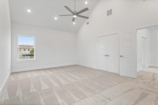 unfurnished bedroom featuring light colored carpet, high vaulted ceiling, and ceiling fan