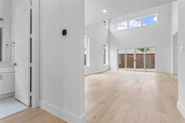 corridor featuring a towering ceiling and light hardwood / wood-style flooring