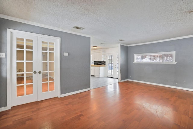 unfurnished living room featuring crown molding, french doors, wood-type flooring, and a textured ceiling