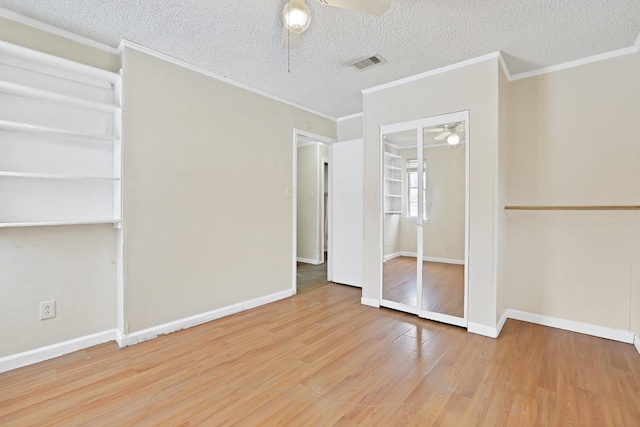 spare room featuring wood-type flooring, a textured ceiling, ceiling fan, and crown molding