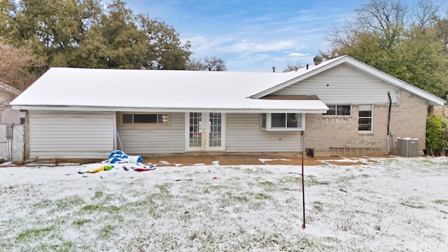 snow covered back of property with central AC and french doors