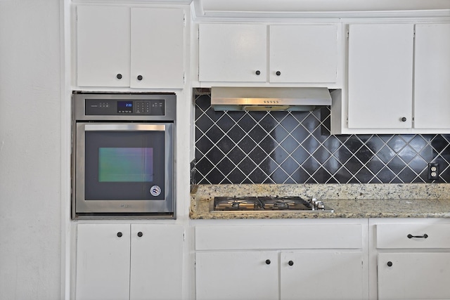 kitchen with backsplash, white cabinets, wall chimney exhaust hood, and appliances with stainless steel finishes