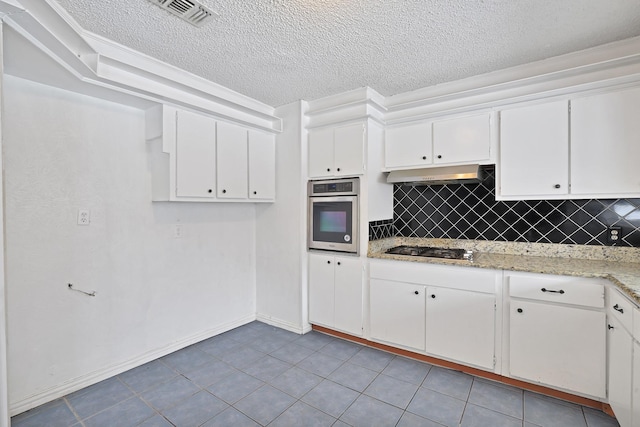 kitchen with a textured ceiling, backsplash, stainless steel appliances, and white cabinetry