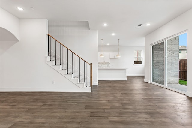 unfurnished living room featuring dark hardwood / wood-style flooring and a healthy amount of sunlight