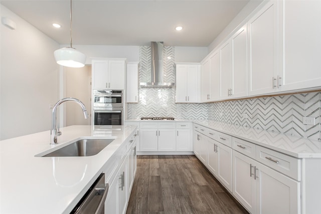 kitchen with white cabinets, wall chimney exhaust hood, sink, and appliances with stainless steel finishes