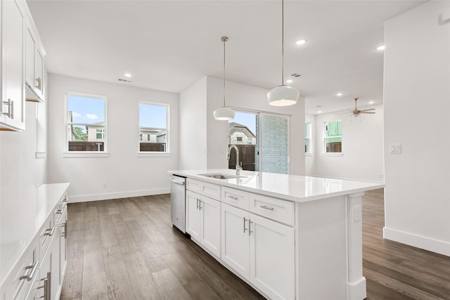 kitchen with dark wood-type flooring, sink, white cabinetry, hanging light fixtures, and an island with sink