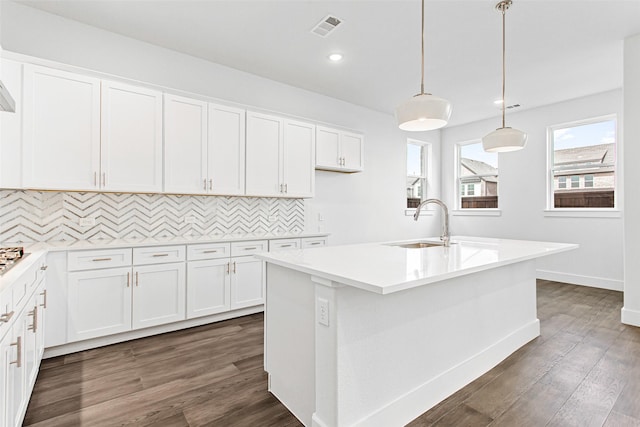 kitchen featuring decorative light fixtures, white cabinetry, and an island with sink