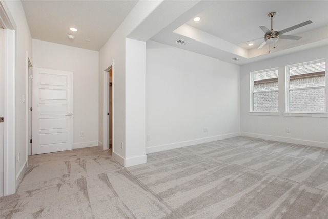 carpeted empty room featuring a tray ceiling and ceiling fan