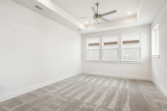 carpeted empty room with a tray ceiling and ceiling fan