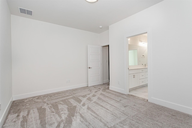 unfurnished bedroom featuring light colored carpet and connected bathroom