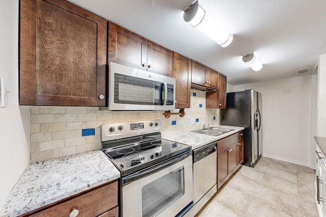 kitchen featuring a textured ceiling, decorative backsplash, sink, and appliances with stainless steel finishes