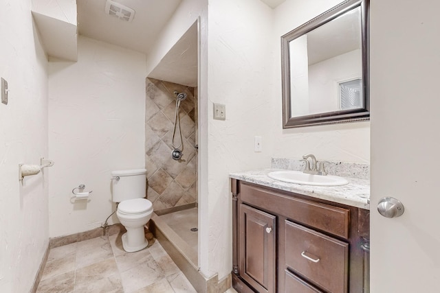 bathroom featuring vanity, toilet, and a tile shower