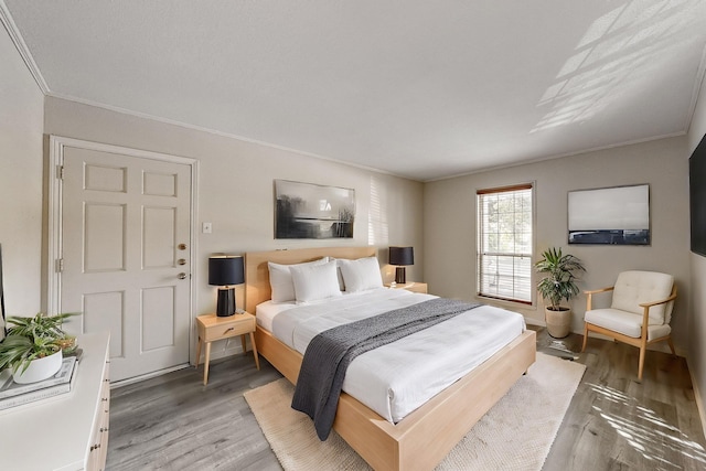 bedroom with hardwood / wood-style floors and ornamental molding