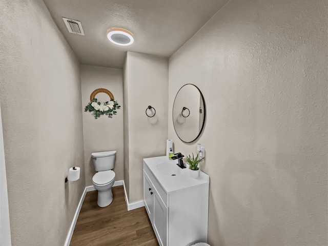 bathroom with vanity, wood-type flooring, a textured ceiling, and toilet