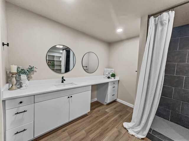 bathroom with hardwood / wood-style floors, vanity, and walk in shower