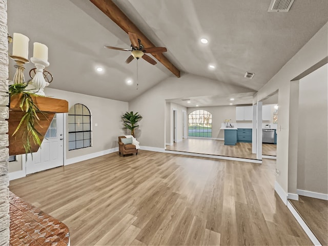 unfurnished living room featuring vaulted ceiling with beams, ceiling fan, and light hardwood / wood-style floors