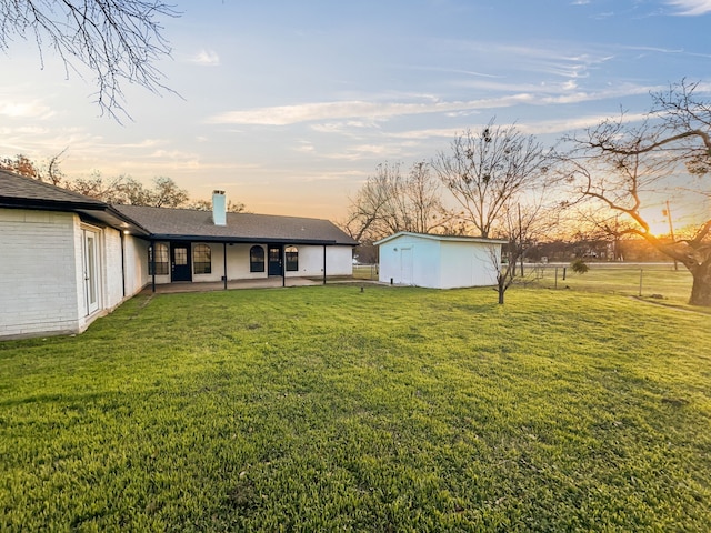 yard at dusk featuring a patio area and an outbuilding