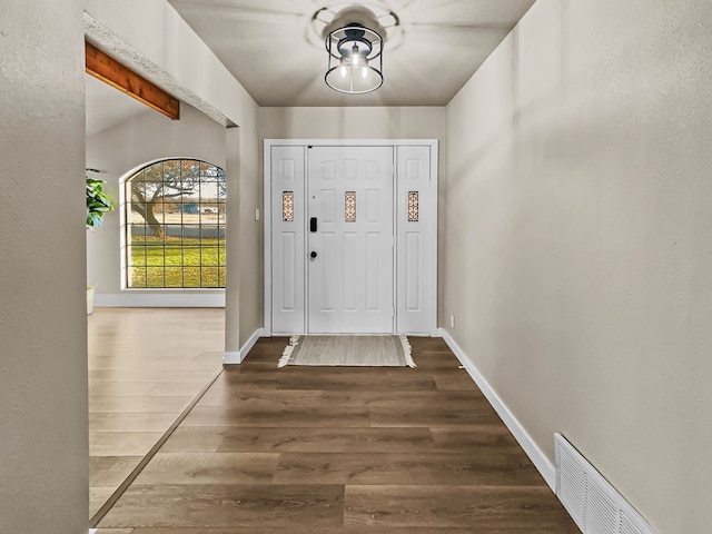 entryway with beam ceiling and dark hardwood / wood-style flooring