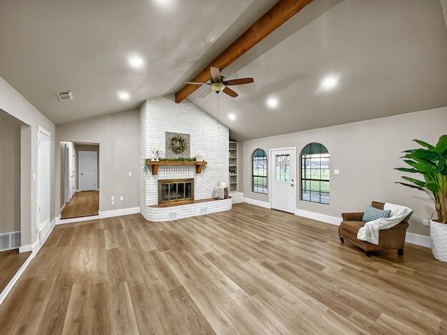 unfurnished living room with vaulted ceiling with beams, ceiling fan, a fireplace, and light wood-type flooring