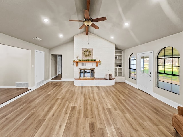 unfurnished living room with vaulted ceiling, ceiling fan, light hardwood / wood-style flooring, built in features, and a fireplace