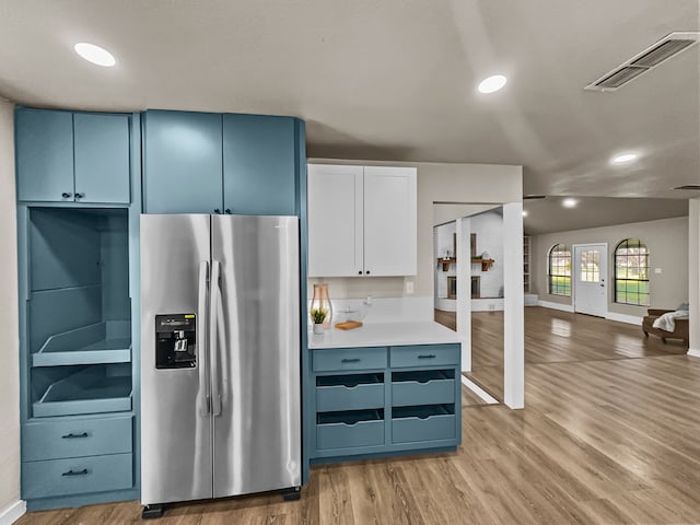 kitchen featuring white cabinets, stainless steel refrigerator with ice dispenser, blue cabinetry, and hardwood / wood-style floors