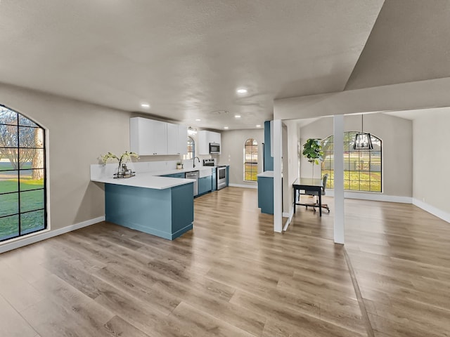 kitchen with white cabinetry, an inviting chandelier, kitchen peninsula, pendant lighting, and appliances with stainless steel finishes