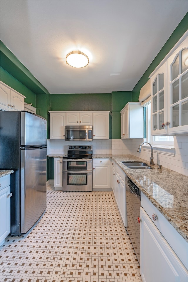 kitchen featuring tasteful backsplash, sink, white cabinets, stainless steel appliances, and light stone countertops