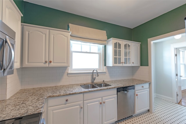 kitchen with glass insert cabinets, dishwasher, decorative backsplash, white cabinetry, and a sink