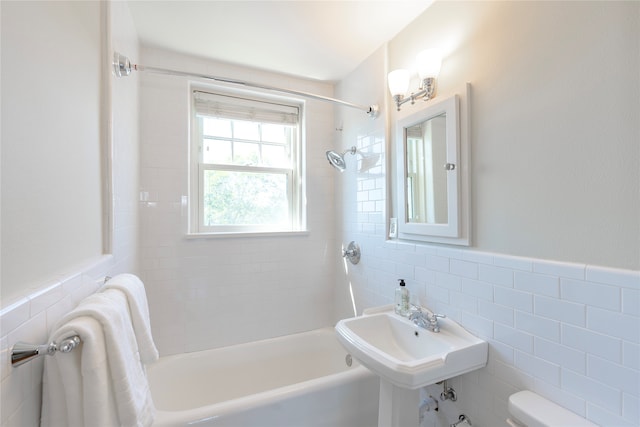 bathroom with toilet, shower / tub combination, wainscoting, tile walls, and a sink