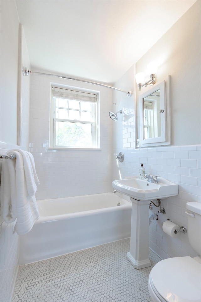 bathroom with tile walls, tiled shower / bath, tile patterned flooring, and toilet