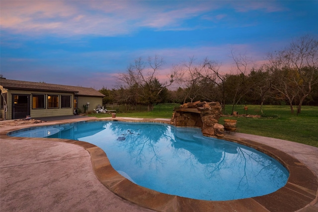 pool at dusk with a yard and a patio