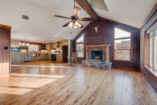 unfurnished living room with sink, ceiling fan with notable chandelier, high vaulted ceiling, a stone fireplace, and light wood-type flooring