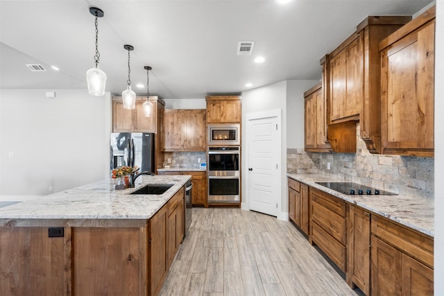 kitchen featuring a large island, sink, hanging light fixtures, decorative backsplash, and appliances with stainless steel finishes