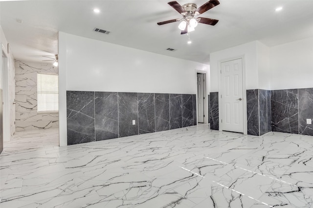 spare room with tile walls and ceiling fan