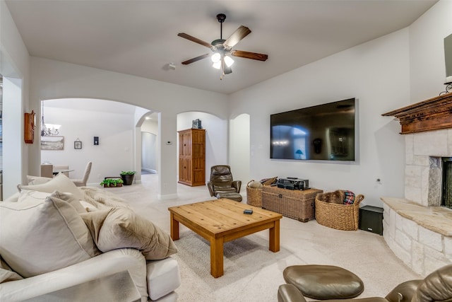 living room featuring a fireplace, light colored carpet, and ceiling fan