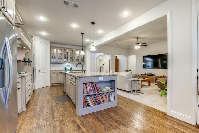 kitchen with hanging light fixtures, an island with sink, sink, and white cabinets