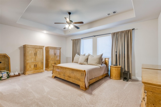 bedroom with carpet floors, ceiling fan, and a tray ceiling