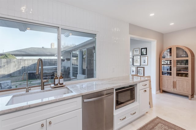 kitchen featuring light stone counters, white cabinetry, sink, and appliances with stainless steel finishes