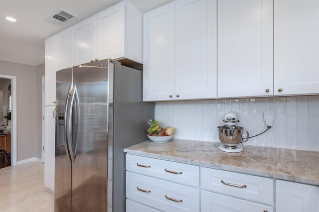 kitchen featuring stainless steel fridge, decorative backsplash, white cabinets, and light stone countertops