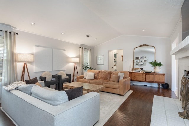 living room featuring hardwood / wood-style floors, vaulted ceiling, ornamental molding, and a brick fireplace