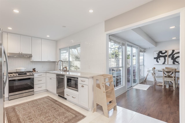 kitchen with stainless steel appliances, white cabinetry, tasteful backsplash, and a healthy amount of sunlight