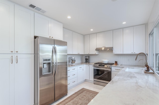 kitchen featuring sink, tasteful backsplash, light stone counters, white cabinetry, and stainless steel appliances