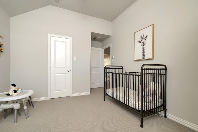 bedroom with a nursery area, vaulted ceiling, and carpet flooring