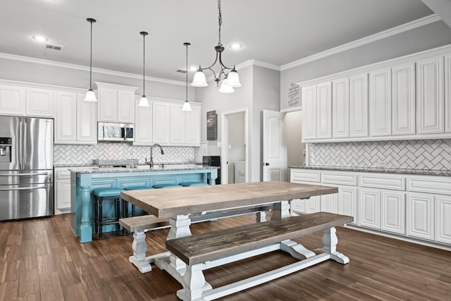 kitchen with stainless steel appliances, white cabinets, and a center island with sink