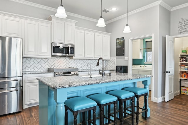 kitchen featuring white cabinets, light stone counters, washing machine and clothes dryer, a kitchen island with sink, and stainless steel appliances