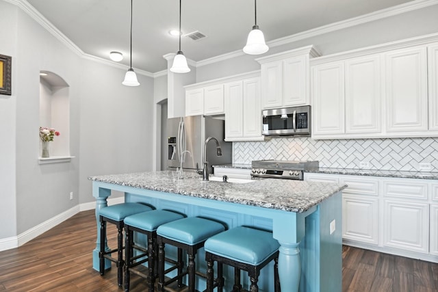 kitchen featuring stainless steel appliances, light stone counters, a center island with sink, and pendant lighting